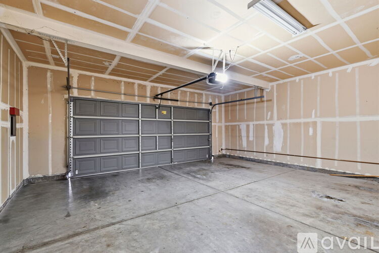 A spacious garage with a closed grey door and a concrete floor.