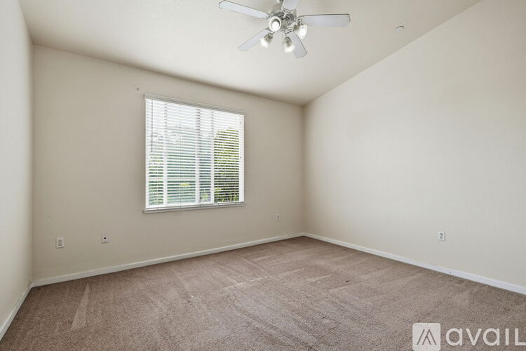 A room with a ceiling fan and a window with blinds.