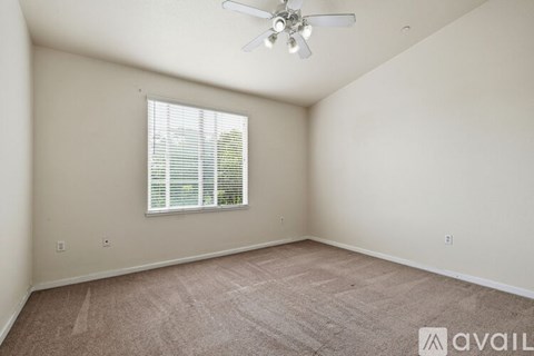 A room with a ceiling fan and a window with blinds.