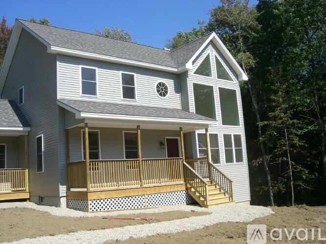 A house with a grey siding and a brown deck.