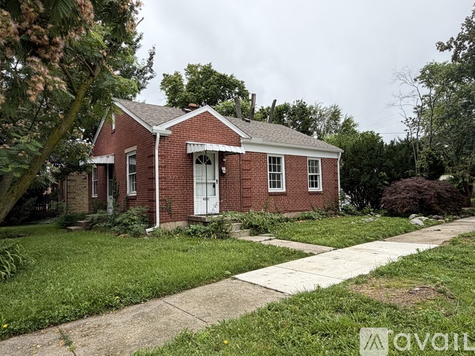 A small red brick house with a white door and windows.