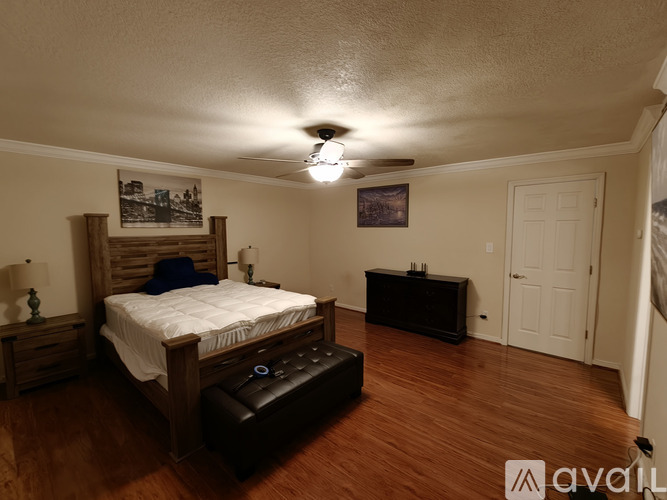 A bedroom with a bed, nightstand, and a painting on the wall.