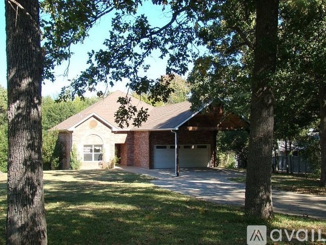 A house with a garage is surrounded by trees.