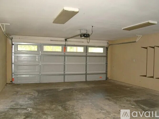 A spacious garage with a grey floor and a large metal garage door.