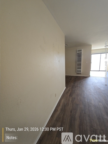 A room with wooden floors and white walls, with a window on the right side.