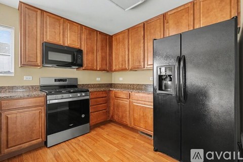 A kitchen with wooden cabinets and a black refrigerator.