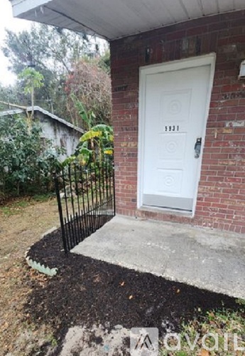 A white door with a black metal railing in front of a brick wall.