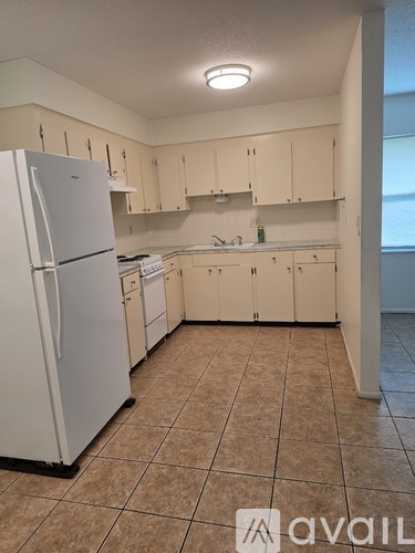 A kitchen with a white refrigerator and white cabinets.