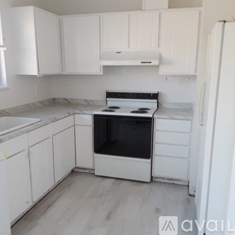 A kitchen with white cabinets and a stove top oven.