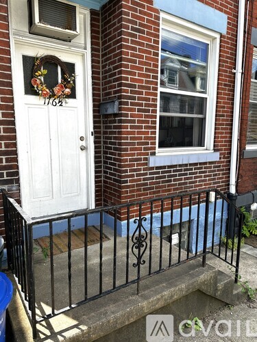 A white door with a wreath on it is on a brick house.