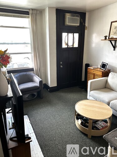 A living room with a grey sofa, a wooden coffee table, and a black door.