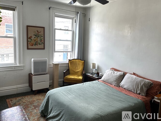 A bedroom with a bed, chair, and window.