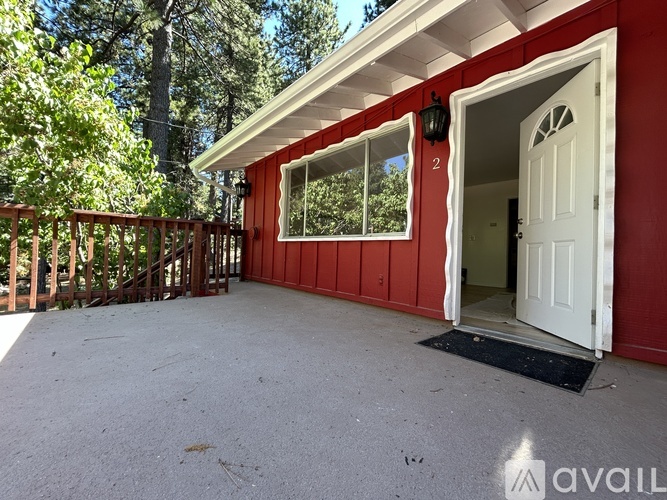 A red house with a white door and a black mat in front of it.