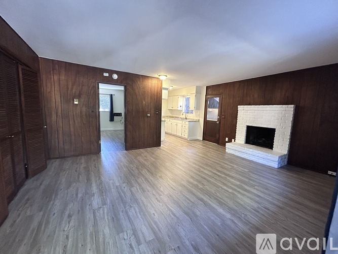 A spacious room with wooden floors and a fireplace.