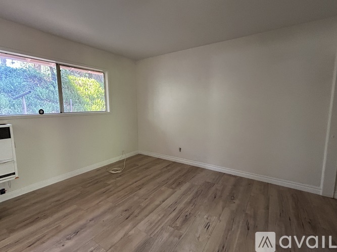 A room with wooden flooring and a window overlooking a garden.