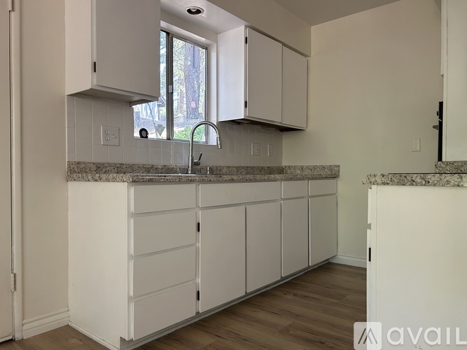 A kitchen with white cabinets and a granite countertop.