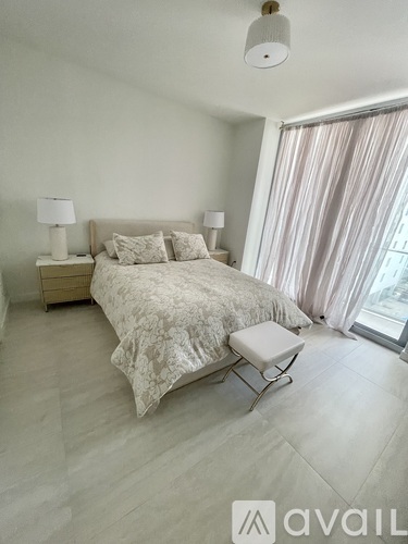 A bedroom with a bed, nightstand, and chair.