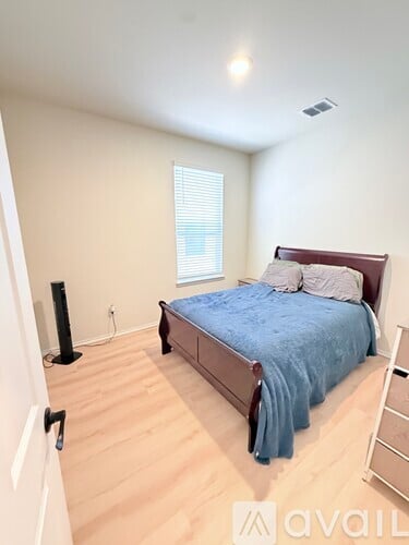 A bedroom with a bed, a window with blinds, and a speaker on the floor.