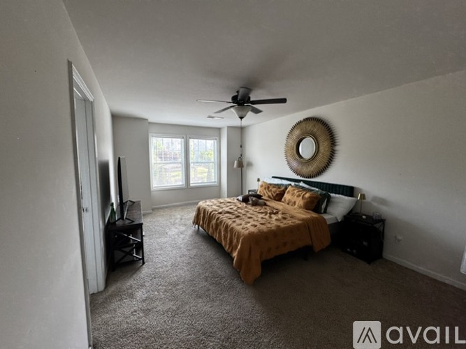 A bedroom with a bed, dresser, and a ceiling fan.