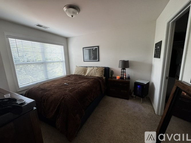 A bedroom with a bed, nightstand, and window.