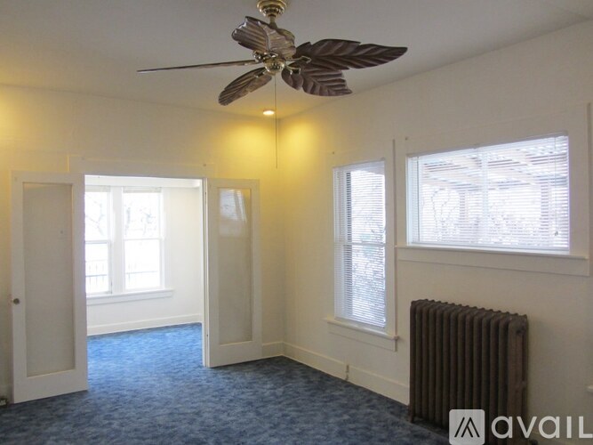 A room with a ceiling fan, two windows, and a radiator.