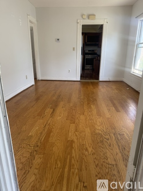 A room with wooden flooring and a doorway leading to another room.