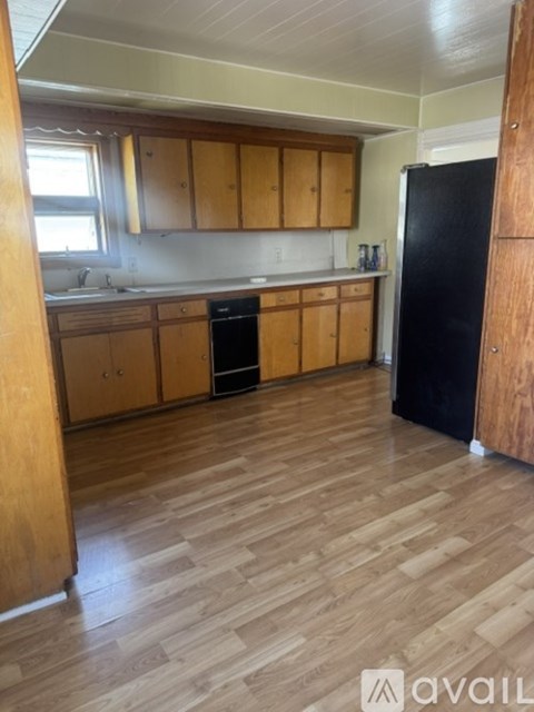A kitchen with wooden cabinets and a black refrigerator.