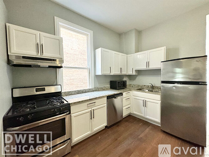 A kitchen with white cabinets and a stainless steel refrigerator.