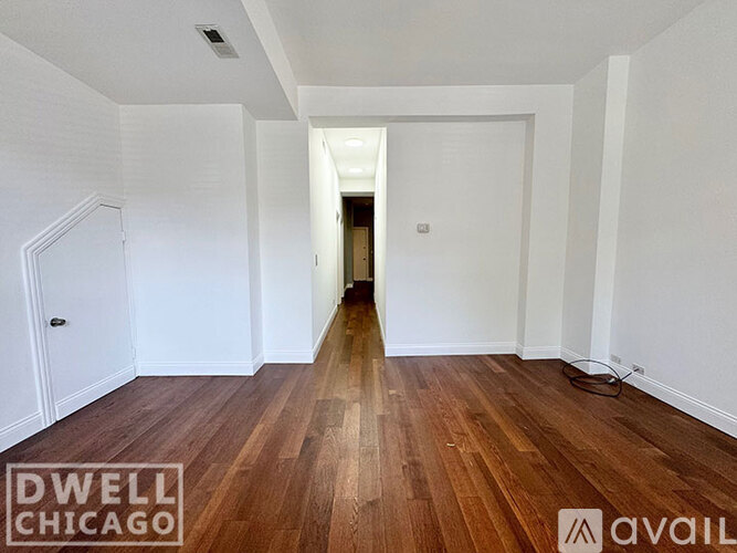 A long hallway with wood floors and white walls.