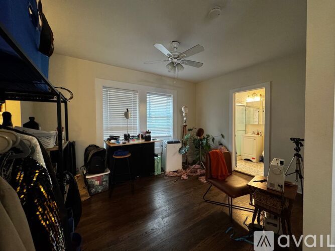 A room with a fan, a table, a chair, and a bicycle.