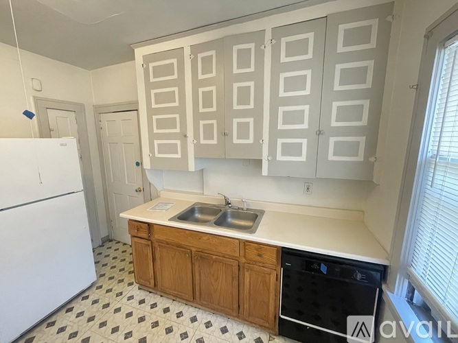 A kitchen with white cabinets and a black and white checkered floor.