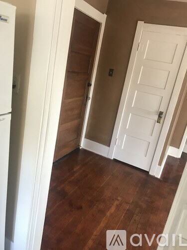 A white door is in a room with brown floors and white walls.