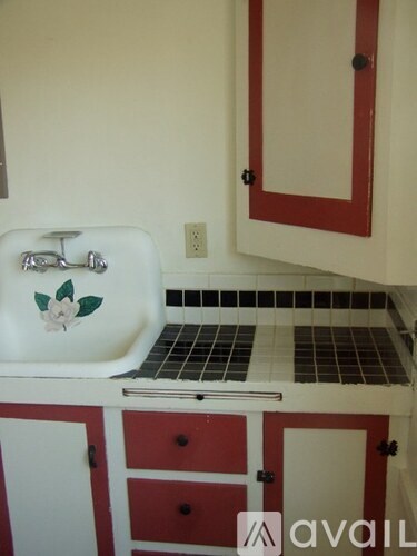 A white sink with a rose on it is in a kitchen.