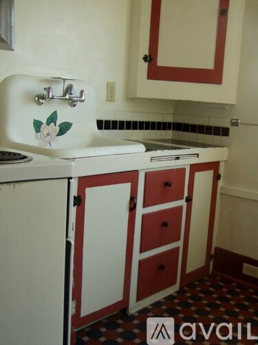 A white sink with a flower design on it is in a small kitchen.