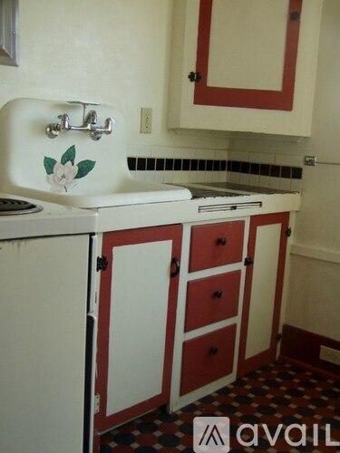 A white sink with a flower design on it is in a small kitchen.