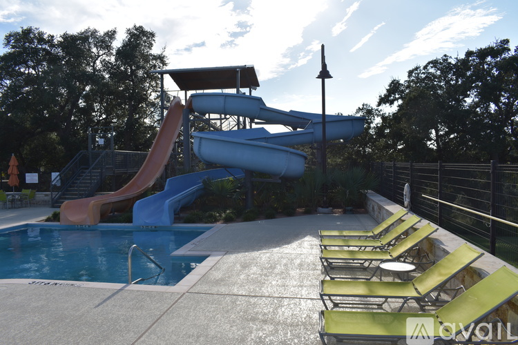 A pool with a slide and sun loungers.
