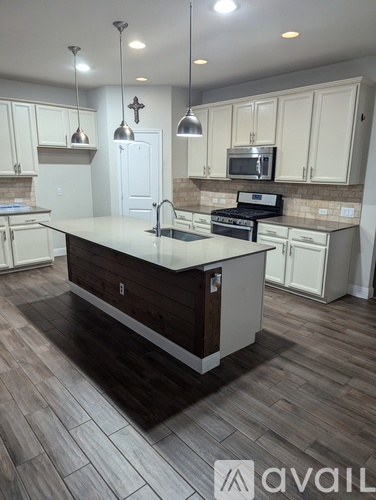 A kitchen with a white counter top and wooden floors.