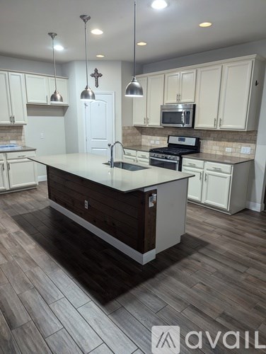 A kitchen with a white counter top and wooden floors.