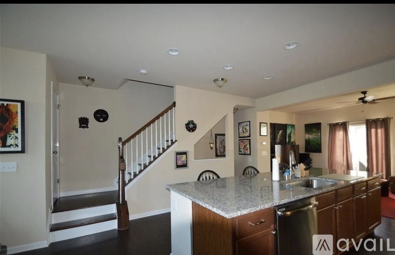 A kitchen with a staircase in the background.
