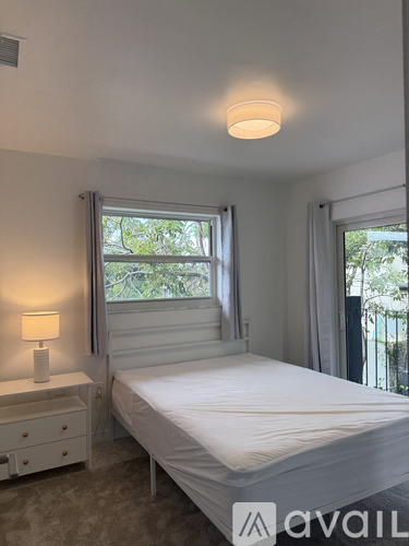 A bedroom with a bed, nightstand, and window.