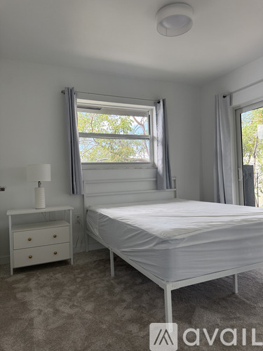 A bedroom with a bed, nightstand, and window.