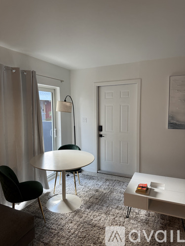 A living room with a white table and black chairs.