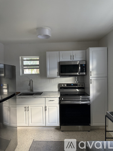 A kitchen with white cabinets and a black stove top oven.