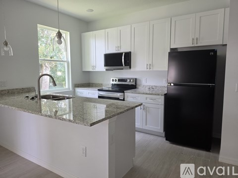 A kitchen with black appliances and white cabinets.