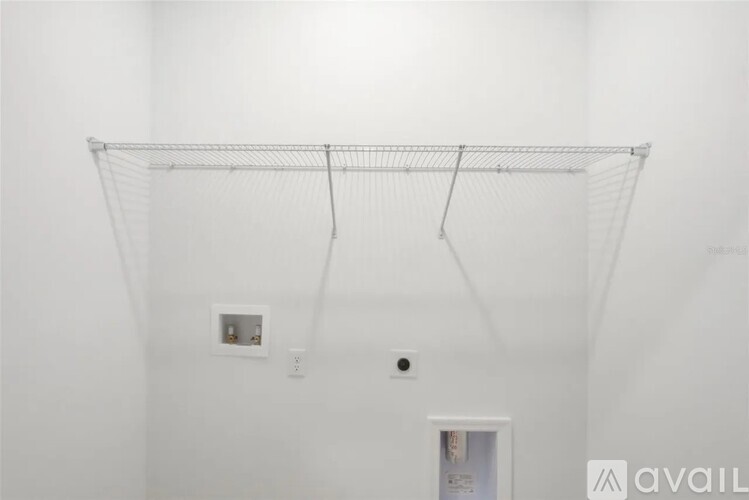 A white wall with a metal rack hanging from the ceiling.