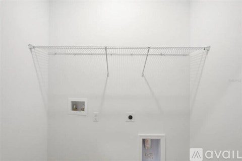 A white wall with a metal rack hanging from the ceiling.