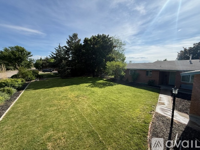A well-maintained lawn in front of a house with a clear blue sky above.