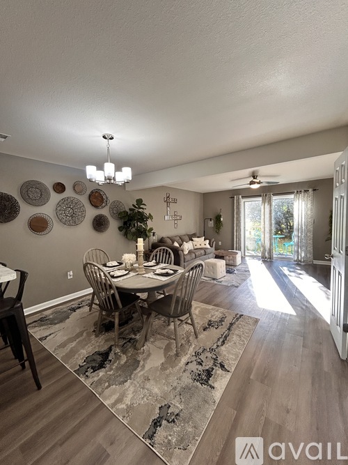 A dining room with a table set for six and a chandelier hanging from the ceiling.