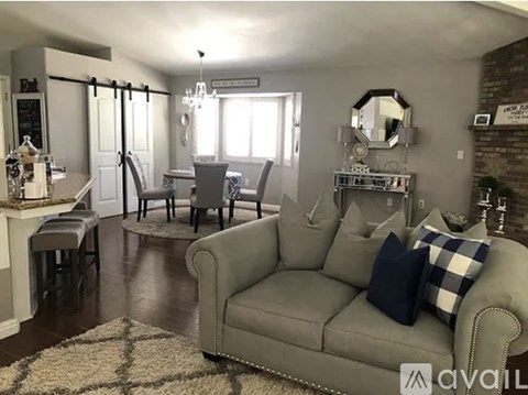 A living room with a grey couch and a chandelier.