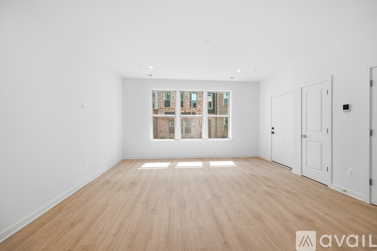 A spacious room with wooden flooring and a large window with a view of a building outside.
